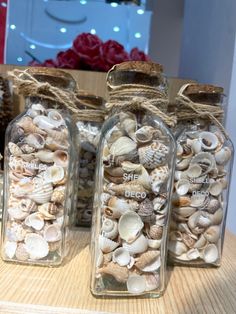 three glass jars with sea shells in them