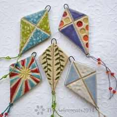 four colorful kites hanging from strings on a white tablecloth with beaded string