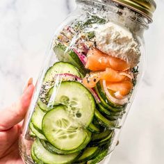 a mason jar filled with cucumbers, tomatoes, and other veggies