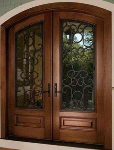 an arched wooden door with glass panels and wrought iron work on the top part of it