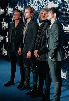 three men standing next to each other in front of a blue wall with stars on it