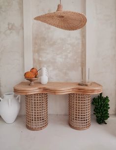 a wooden table with two baskets on it and a white vase next to the table