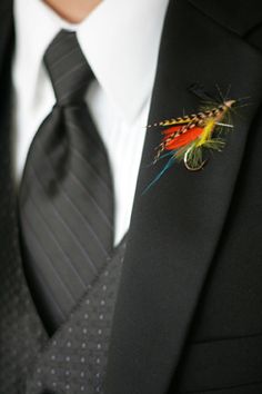 a man wearing a black suit and tie with a fish pin on it's lapel