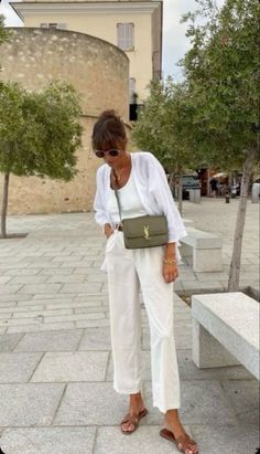 This look is all about understated elegance! A flowing cream white pants paired with a matching top and blouse create a chic and timeless outfit. Adding a pop of color with a green bag makes it perfect for any occasion.   #EffortlessElegance#CreamWhiteOutfit #MinimalistFashion#ChicStyle#TrendyOutfits #FashionInspiration#SummerStyle #FashionTrends#CasualChic#StreetStyle#OutfitIdeas #FashionLovers#StyleInspo#TrendyOutfits#Fashion #Style#OutfitOfTheDay#Summeroutfits Italian Summer Womens Fashion, Womens Italy Outfit, European Fashion For Women Over 50, Italy Street Fashion Summer, Summer Sun Protection Outfit, Outfit In Italy Summer, Paris Summer Fashion 2023, Chic European Style Outfit Summer, Summer In Italy Fashion