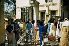 a group of women walking down a street next to tall buildings with bicycles parked in front of them