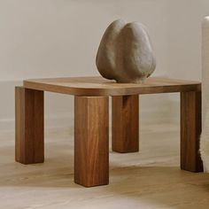 a small wooden table with a stone sculpture on it's top next to a chair