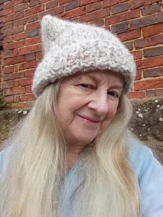 an older woman with long blonde hair wearing a knitted hat