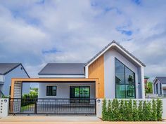 a house that is in the middle of some grass and bushes with windows on each side