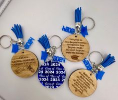 three wooden keychains with blue tassels on them, one for graduation