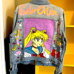 a denim jacket with an image of sailor moon on the front and back, hanging in a closet