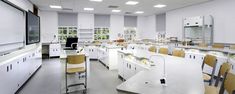 an empty lab with many tables and chairs in it's center area, while the lights are on