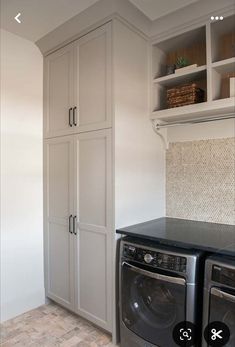 a washer and dryer in a room with white cabinets on the wall above them