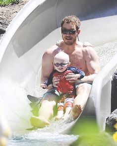 a man and child are riding on a water slide