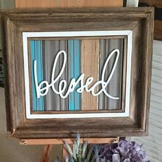 a framed sign that says, be loved on it next to some flowers and a potted plant