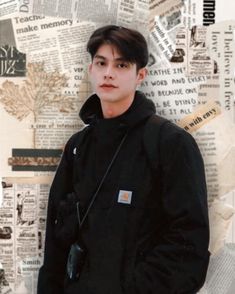 a young man standing in front of a newspaper wall