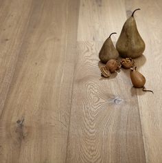 two pears and some nuts on a wooden floor