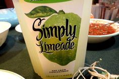 a bottle of simply limeade sitting on top of a table next to bowls of food