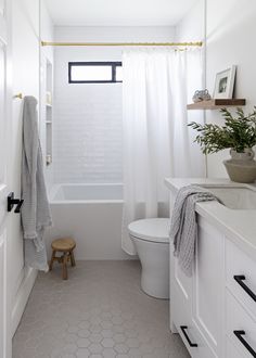 a bathroom with a toilet, sink and bathtub next to a white shower curtain