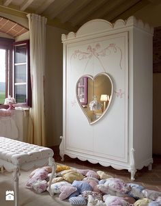 a bedroom with a white armoire and pink pillows on the floor next to it