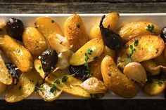 roasted potatoes with olives and parsley in a white dish