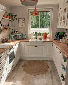 a kitchen filled with lots of white cabinets and wooden counter top space next to a window