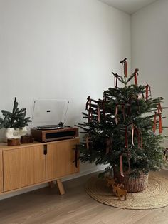 a small christmas tree in a room next to a record player and wooden cabinet with ribbon on it