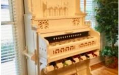 an old white piano sitting in front of a window