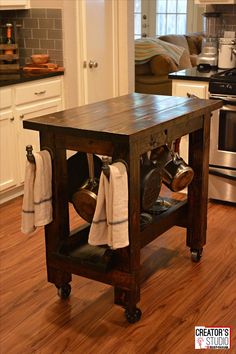 a kitchen island with pots and pans on it in the middle of a wooden floor