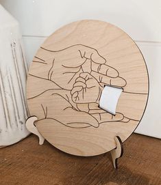 a wooden plate with a drawing of two hands holding a piece of paper on it