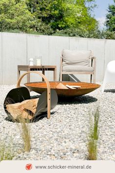 an outdoor seating area with chairs and a table in the middle, surrounded by gravel