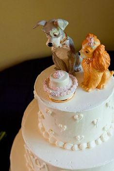 a three tiered white cake with dogs on top and other figurines atop it