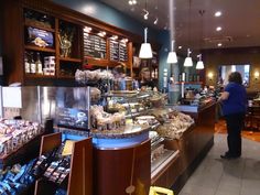 a woman standing in front of a counter filled with lots of food and drink items