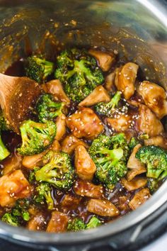 chicken and broccoli stir fry in the crock pot with a wooden spoon