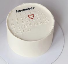 a white cake with a red heart on it and the date november written in cursive writing