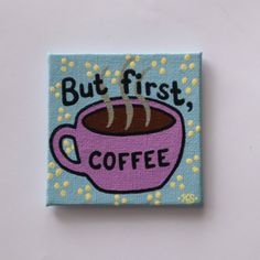 a blue square magnet with a pink coffee cup on it that says, but first, coffee