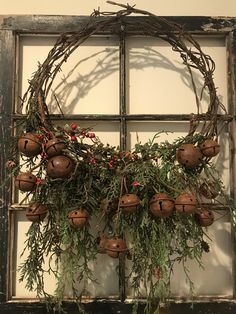 an old window with a wreath and bells hanging from it