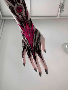 a person's hand with black and pink designs on it, hanging from the ceiling