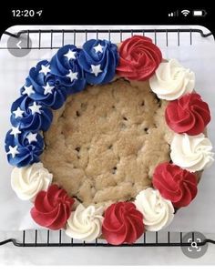 a cookie cake decorated with red, white and blue icing on a cooling rack