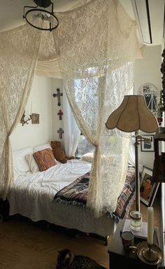 a white bed sitting under a window next to a lamp on top of a hard wood floor