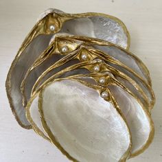 five pieces of silver and gold with pearls on them, sitting on a white surface