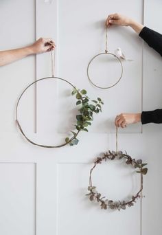 two hands are hanging wreaths on the wall and one is holding a flower crown