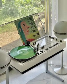 a record player sitting on top of a white table next to a green vinyl record