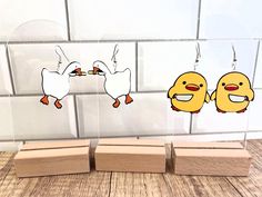 three wooden blocks with cartoon characters hanging from them, one is yellow and the other is white