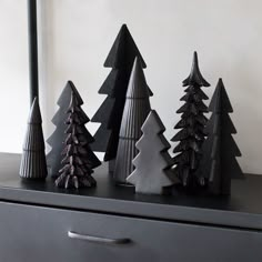 three black christmas trees sitting on top of a dresser