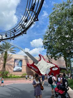 people are walking around in front of a guitar sculpture