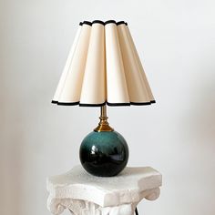 a lamp sitting on top of a white table next to a black and white vase