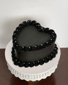 a heart shaped black cake sitting on top of a table