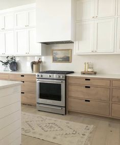 a kitchen with white cabinets and stainless steel stove top oven in the center, along with an area rug on the floor