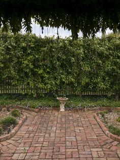 a brick walkway with an ornamental urn in the center surrounded by trees and bushes