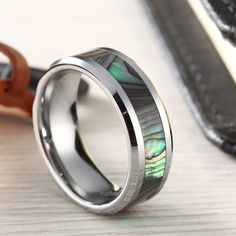 a wedding ring with abangani shell inlays sits on a table next to a pair of scissors